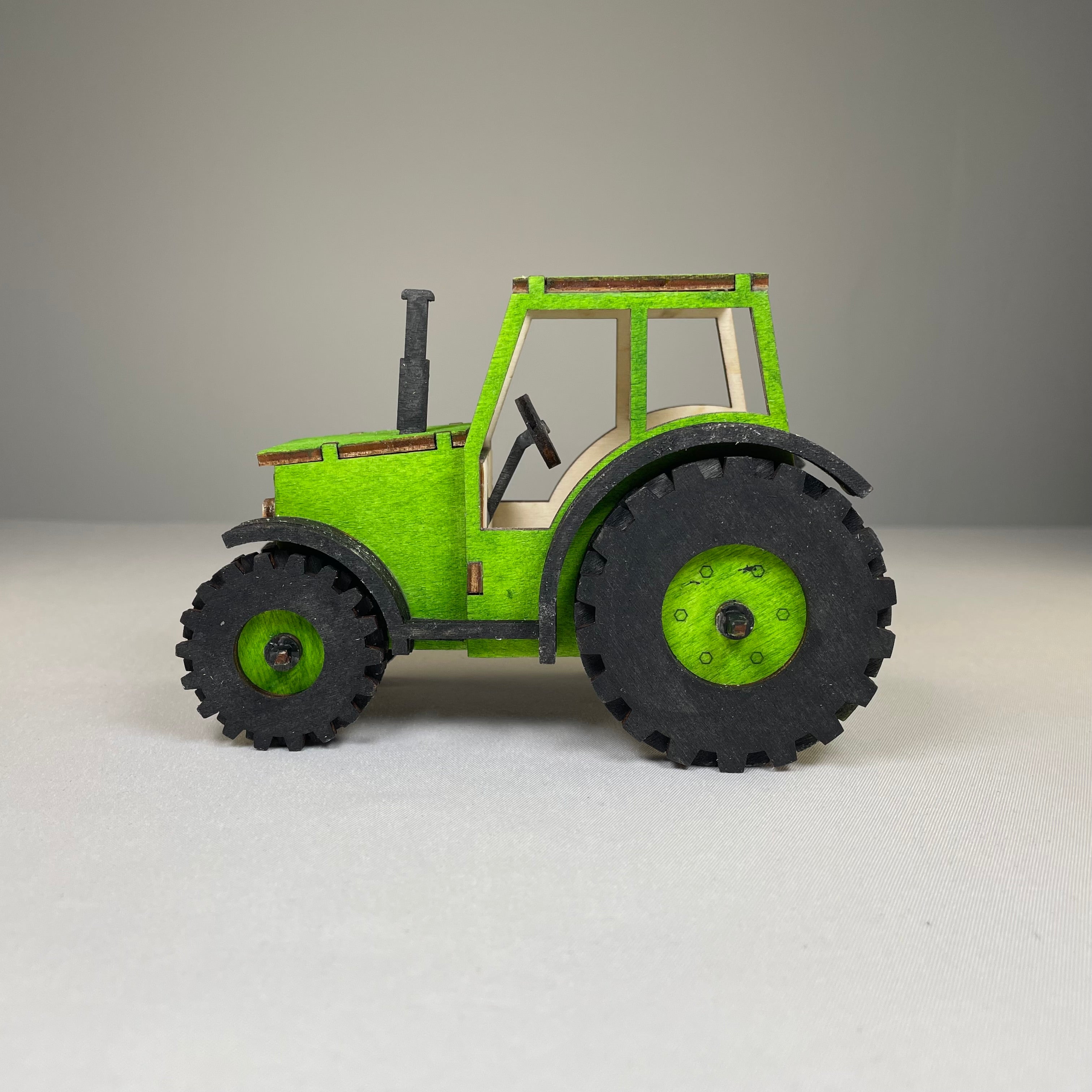 Curious Rabbit garden tractor puzzle flatpack model kit, showing assembled colorful tractor with detailed parts and garden background.