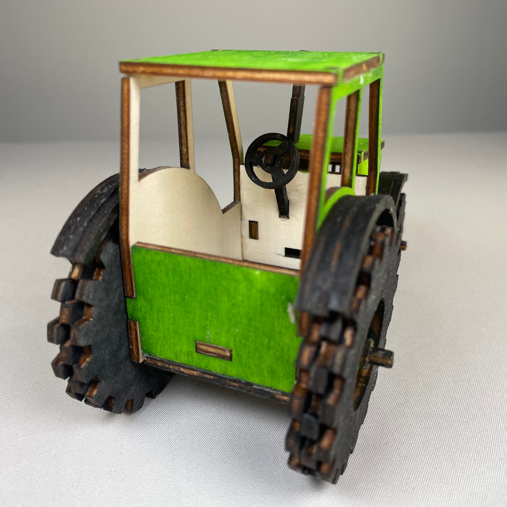Garden tractor puzzle by Curious Rabbit, flatpack model kit showing assembled tractor with detailed parts and vibrant colors.