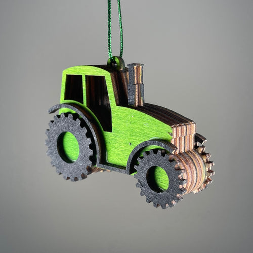 Handmade Curious Rabbit garden tractor bauble ornament hanging with greenery and flowers in the background.