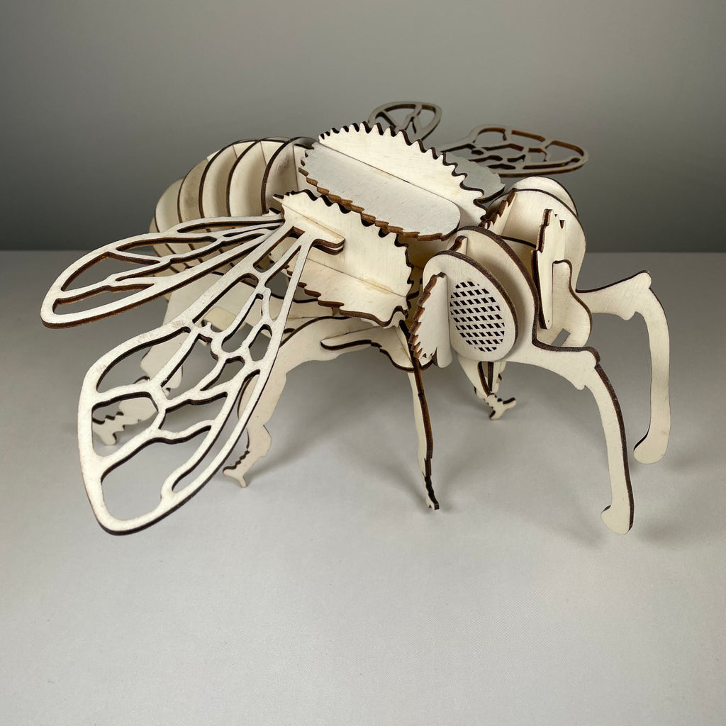 Curious Rabbit bee garden puzzle flatpack model kit with assembled bee-shaped structure and vibrant garden background.