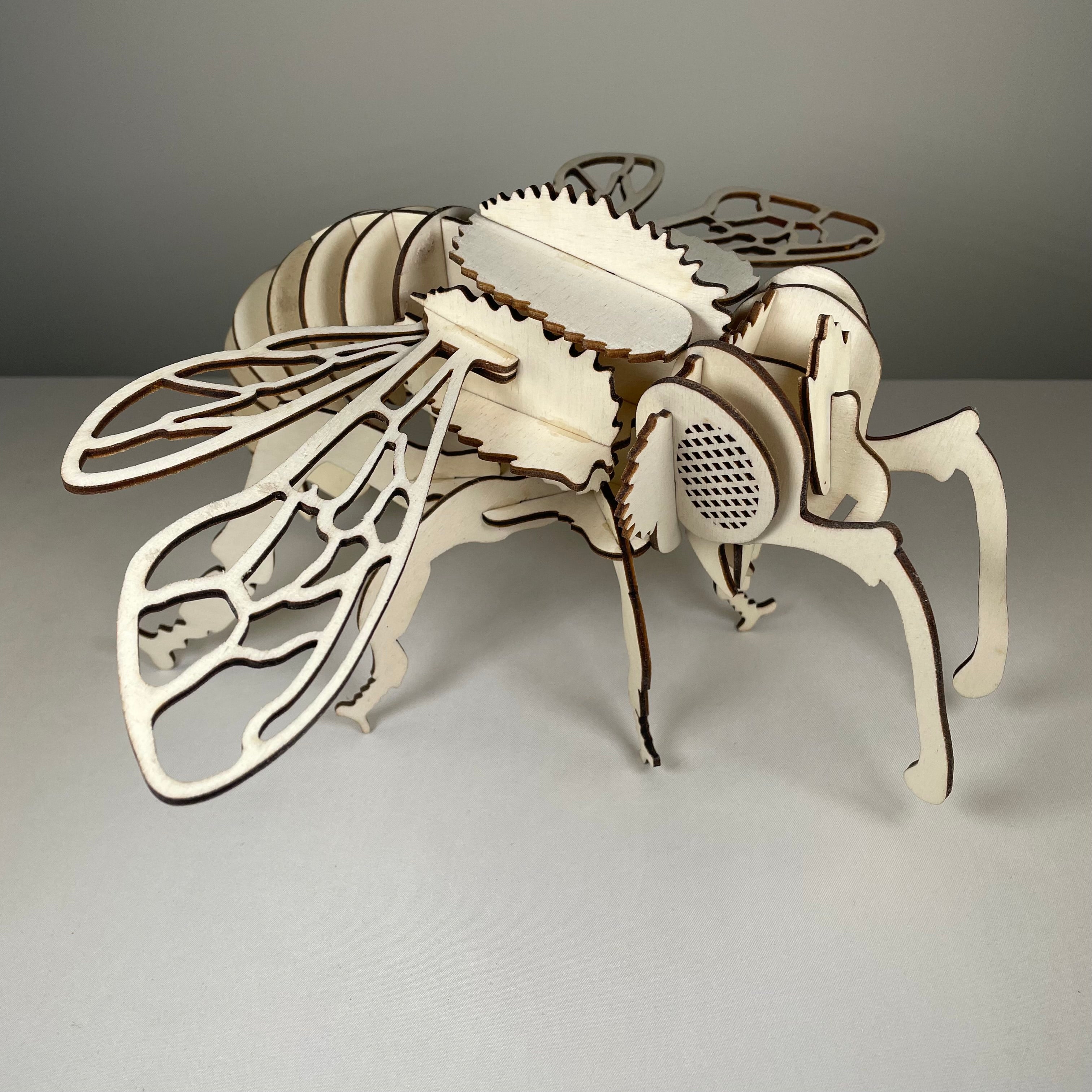 Curious Rabbit bee garden puzzle flatpack model kit with assembled bee-shaped structure and vibrant garden background.