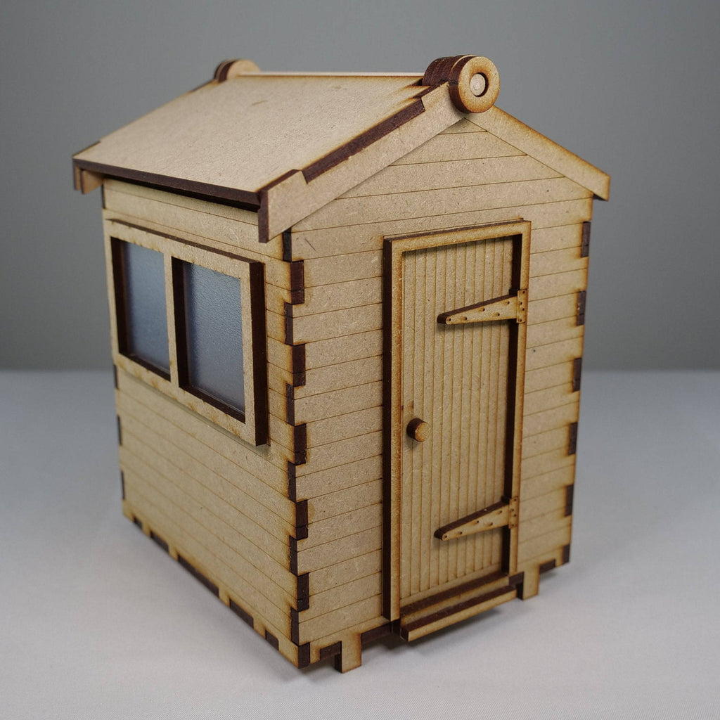 Curious Rabbit garden shed flatpack model kit with wooden panels, doors, and assembly components for outdoor storage.
